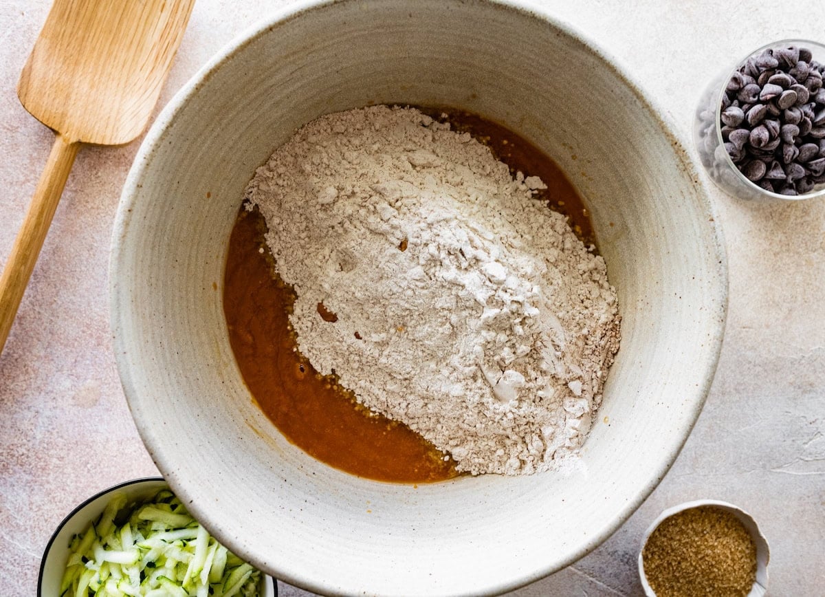 dry ingredients being added to pumpkin mixture in mixing bowl.