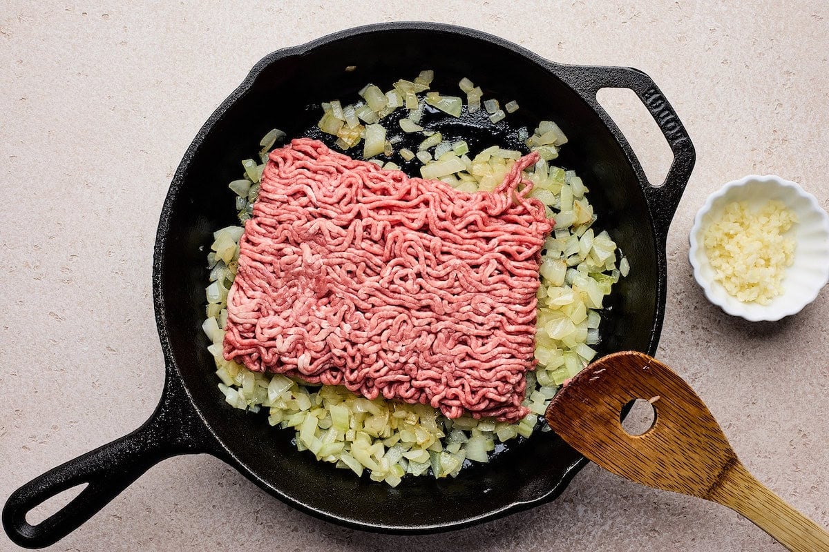 ground beef and onions in cast iron skillet.