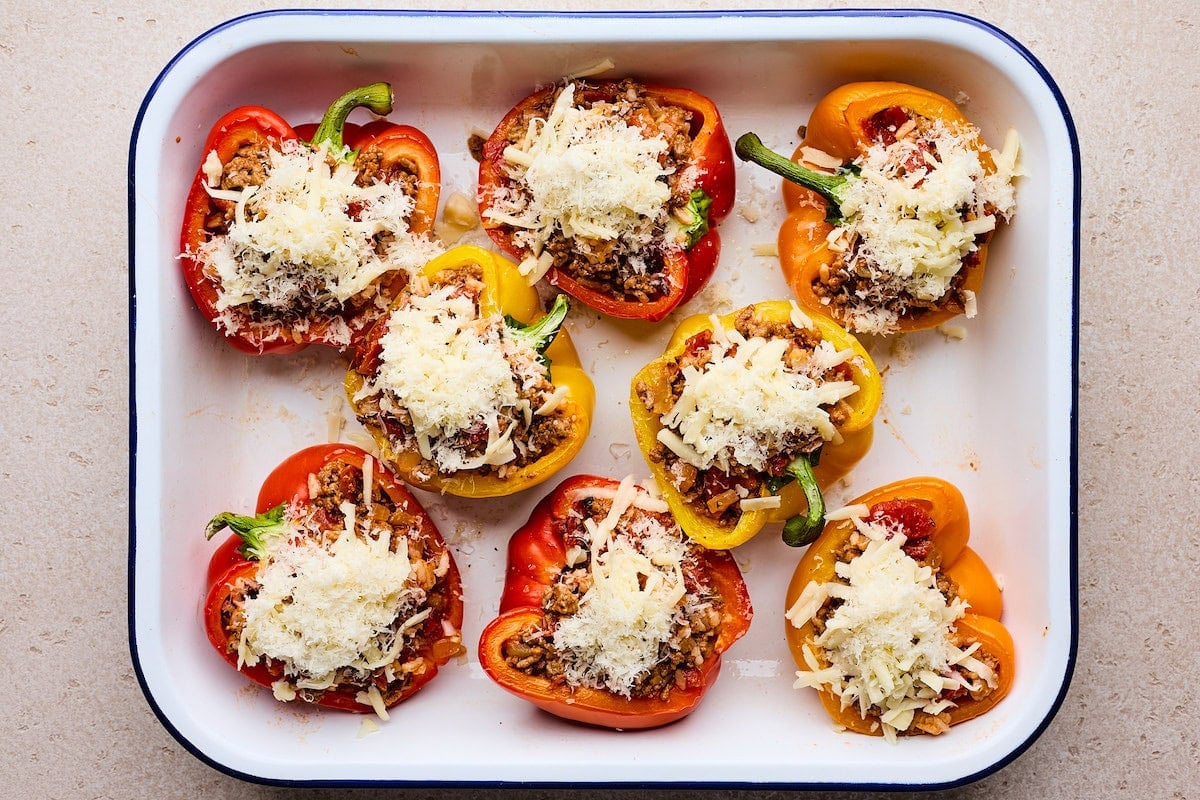 stuffed peppers in pan with meat mixture and shredded cheese ready to go in oven.