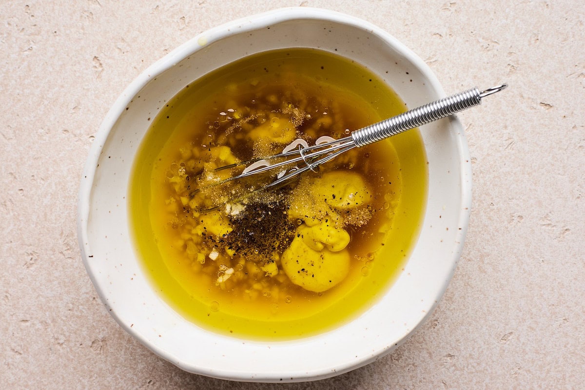 maple mustard dressing in bowl with whisk.