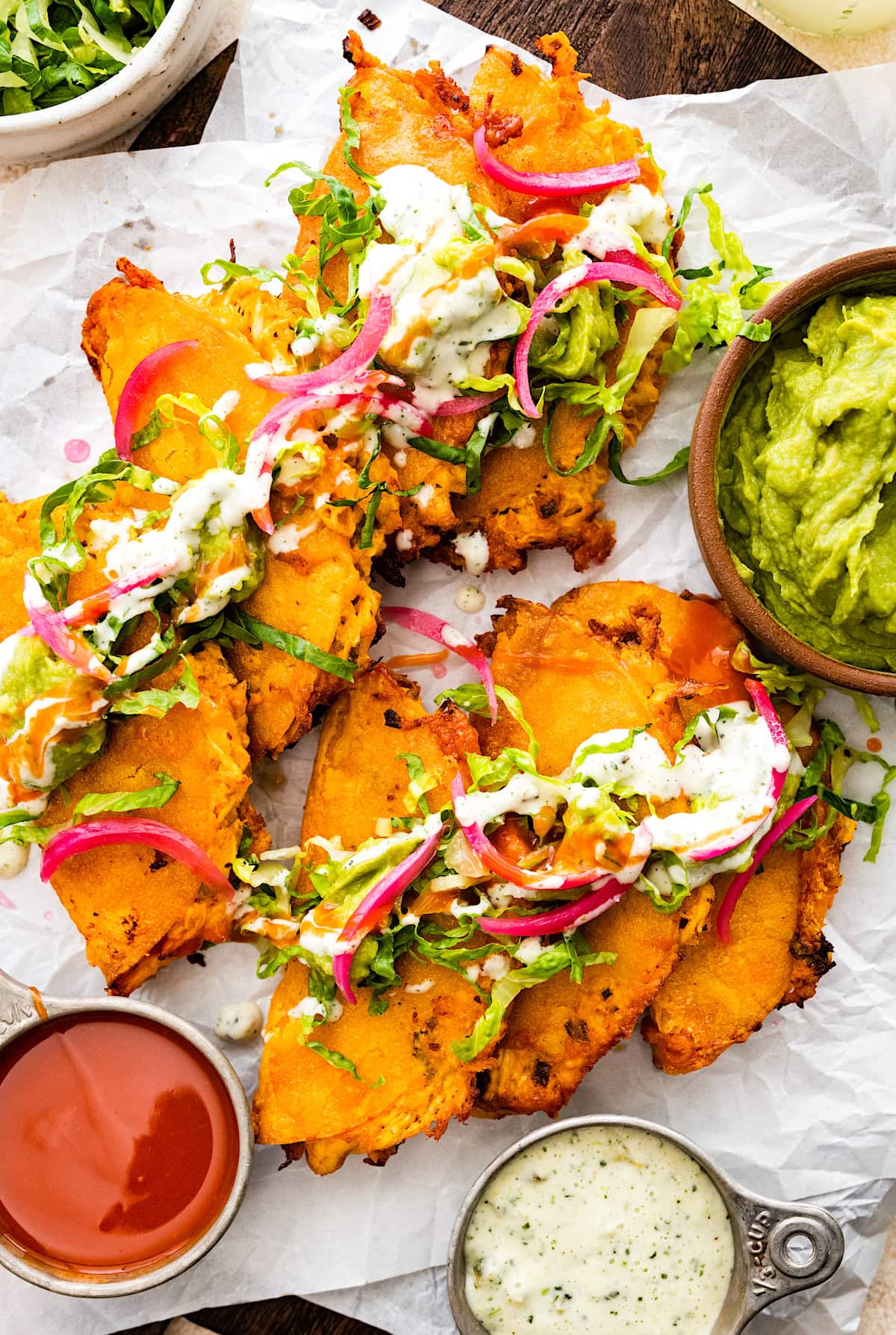 crispy buffalo chicken tacos with pickled red onions, guacamole, lettuce, and crema.