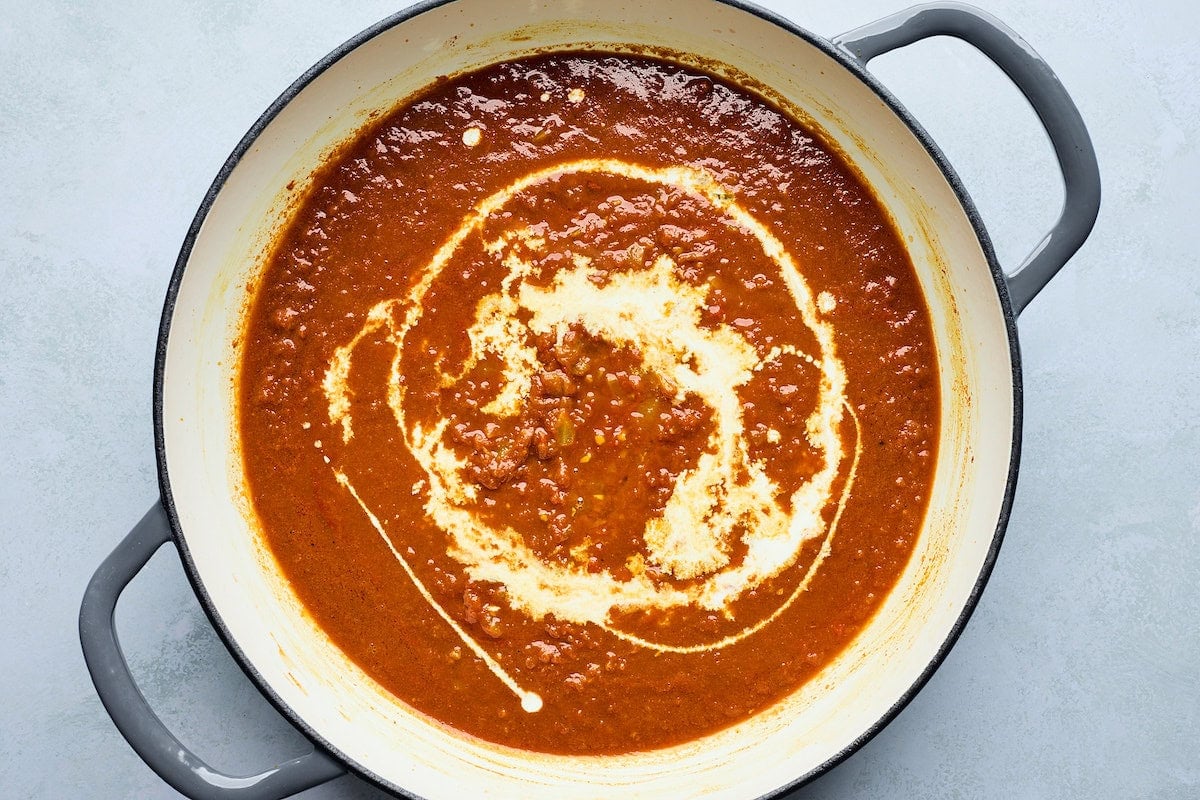tikka masala sauce in pot with swirl of heavy cream.