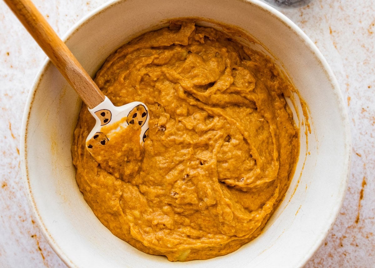 pumpkin banana muffin batter in mixing bowl with spatula.