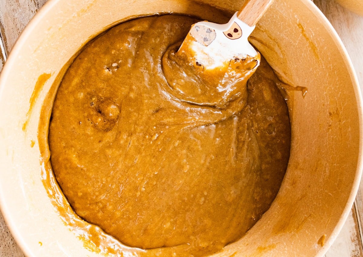 apple cake batter in mixing bowl with spatula.