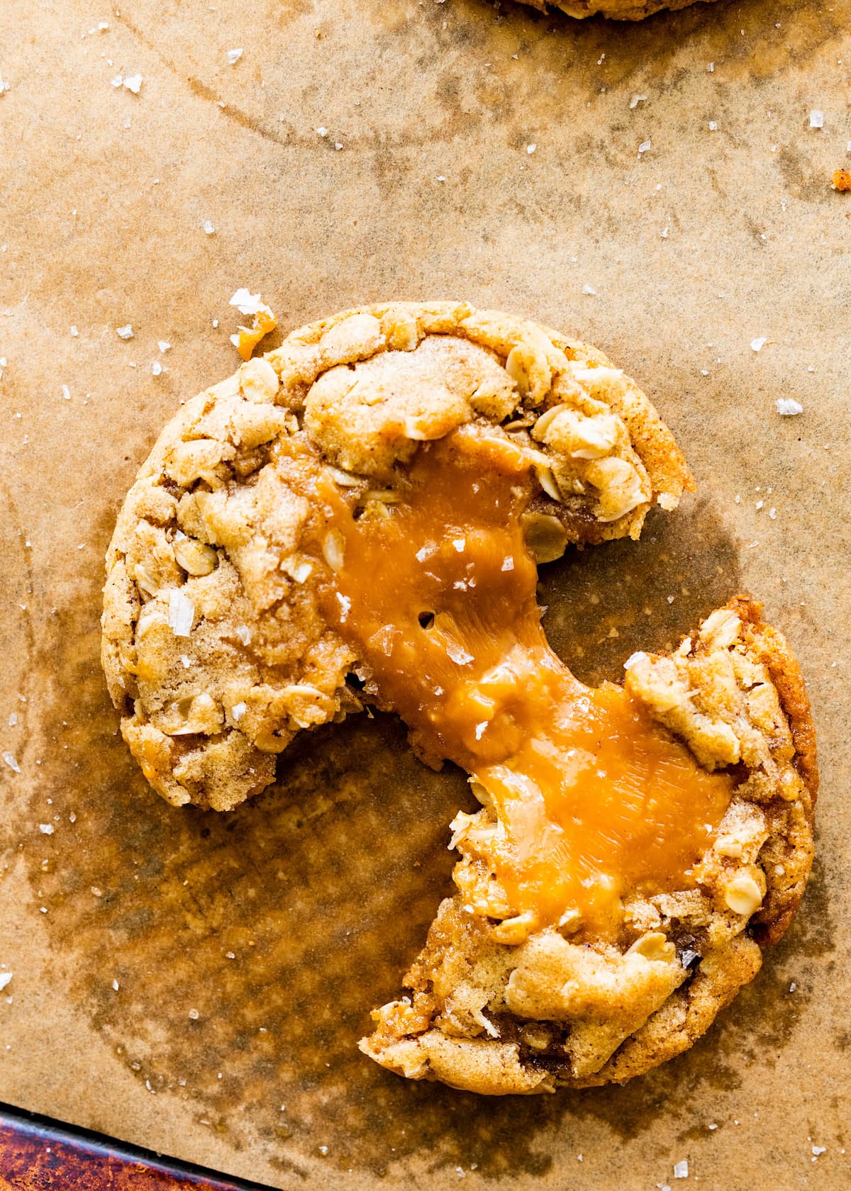 brown butter caramel oatmeal cookie broken in half with a caramel pull.