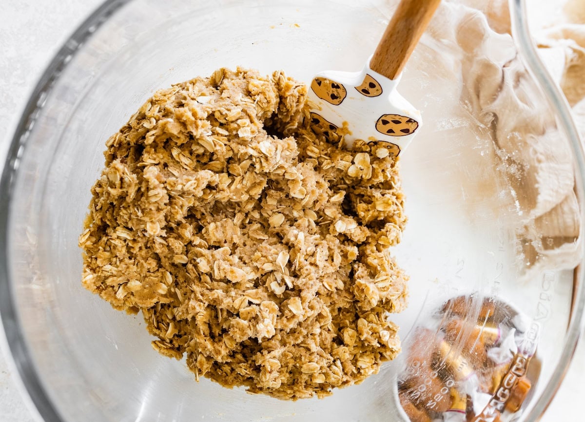 iced oatmeal cookie dough in mixing bowl with spatula.