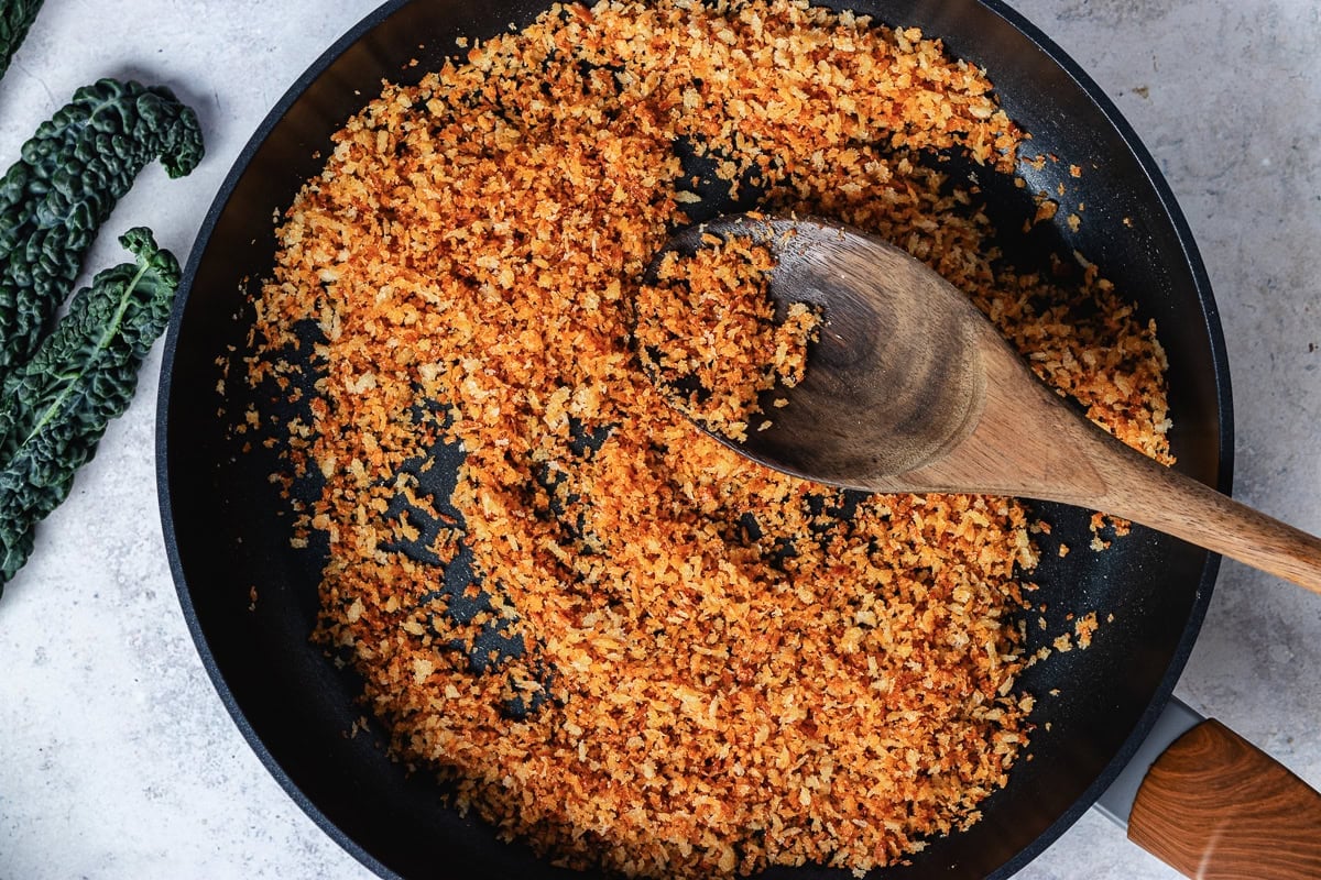toasted breadcrumbs in skillet with wooden spoon.