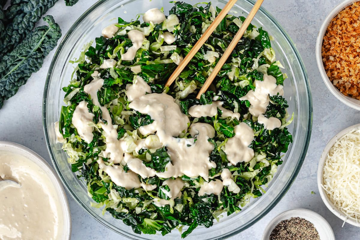 shredded Brussels Sprouts and kale in bowl with Caesar dressing.
