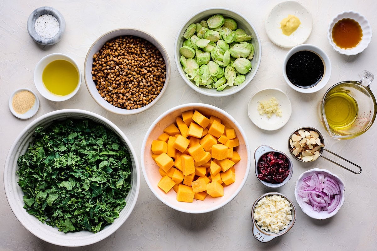 ingredients in bowls to make kale salad with roasted vegetables and crispy lentils.