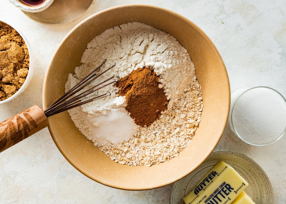 oats, flour, cinnamon, nutmeg, baking soda, baking powder, and salt being whisked in mixing bowl.