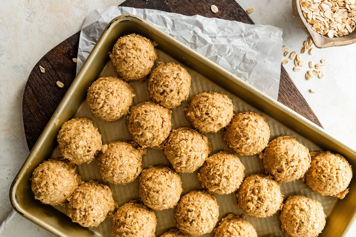 iced oatmeal cookie dough balls on baking sheet.