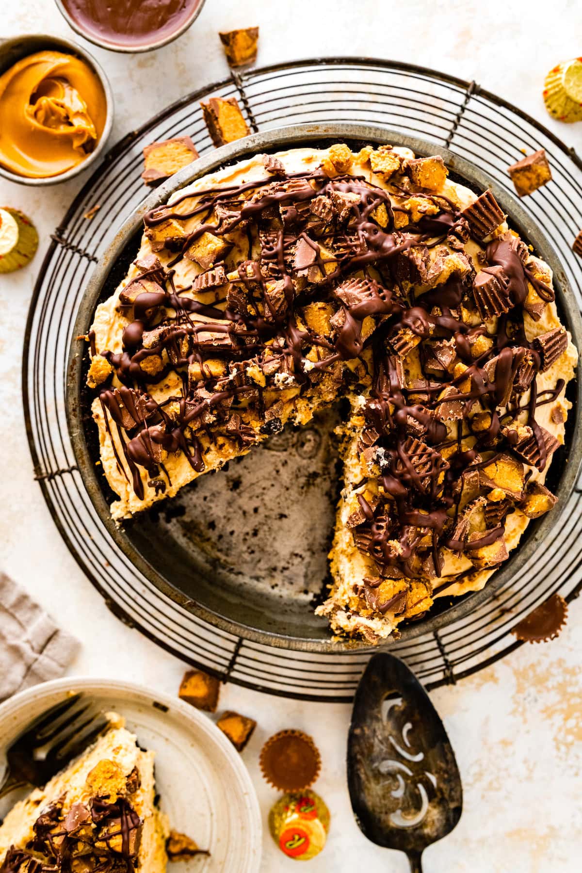 peanut butter pie in pie pan with peanut butter cups and chocolate drizzle.