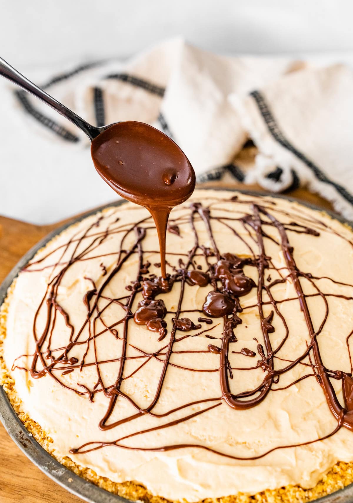 chocolate being drizzled over a salted caramel pie.