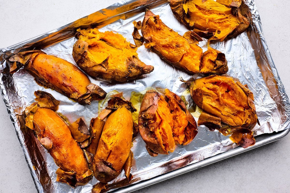 peeling baked sweet potatoes on baking sheet.