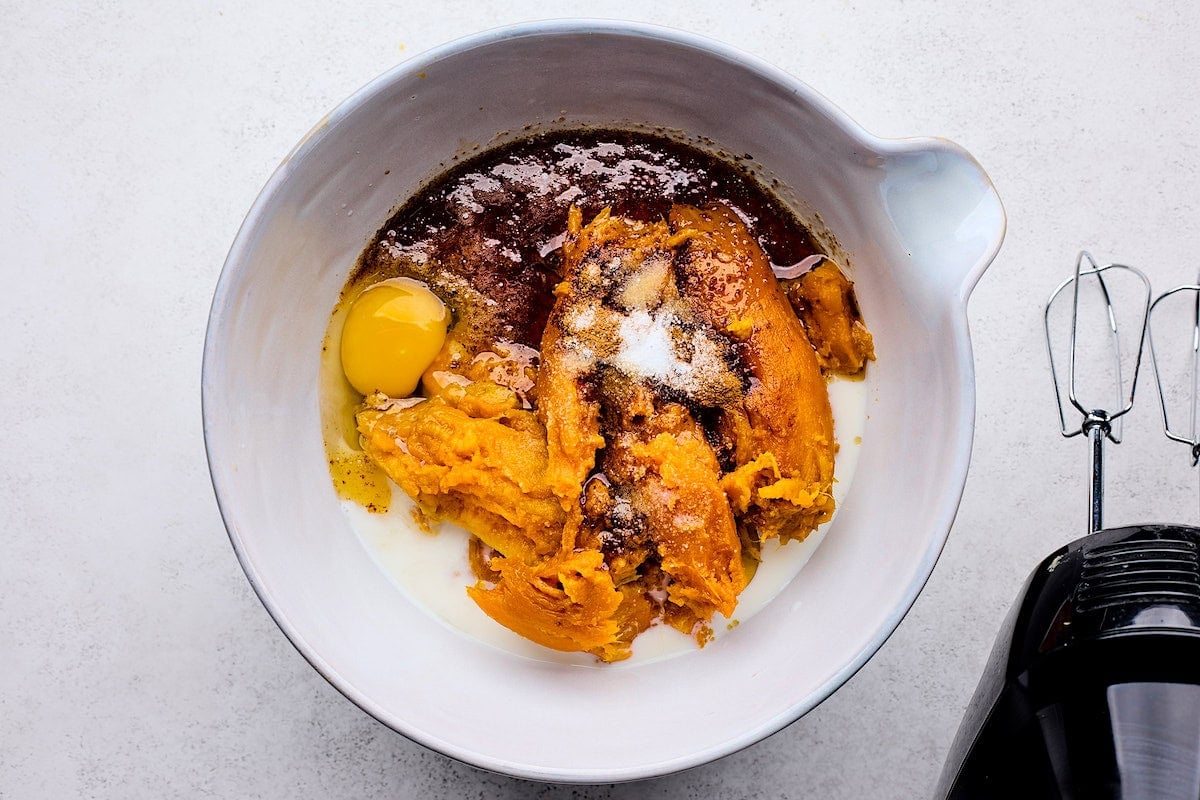 sweet potato casserole filling in mixing bowl with hand held mixer.