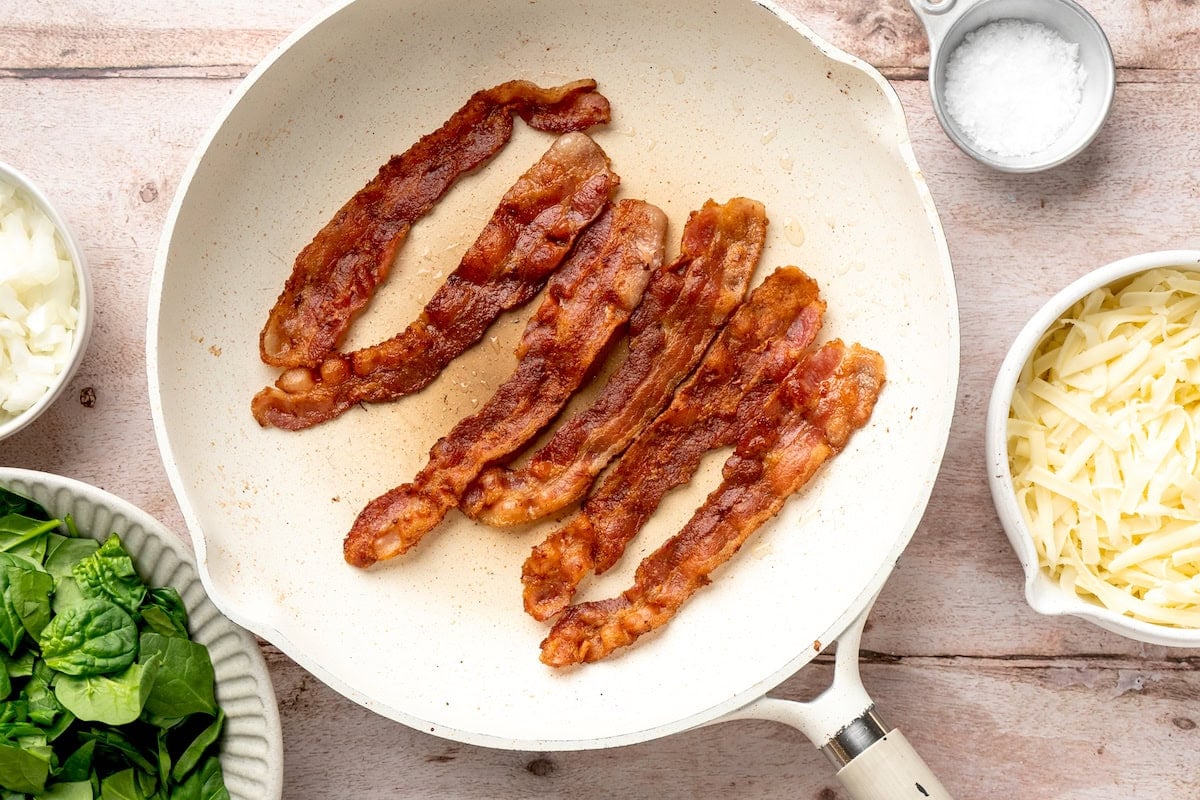 bacon strips cooking in skillet.