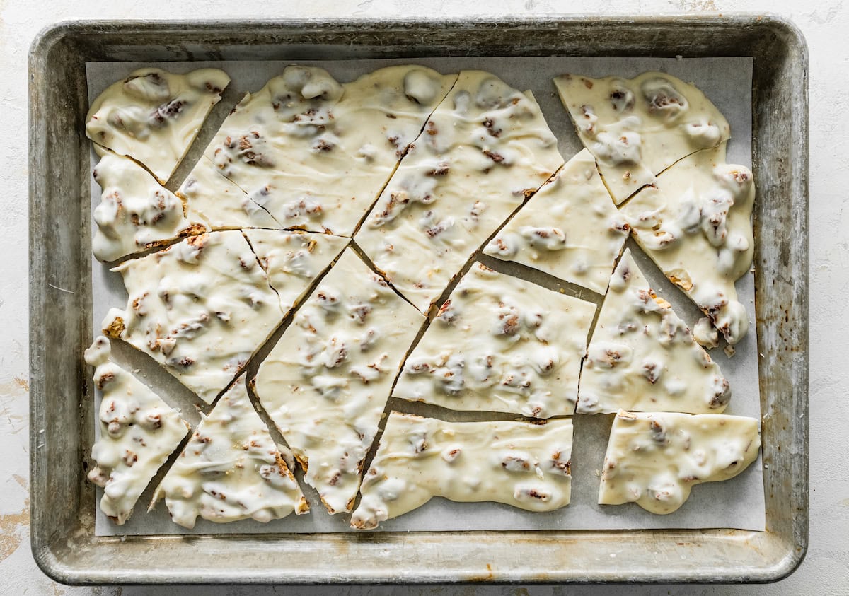 white chocolate candied pecan bark broken into pieces on baking sheet.