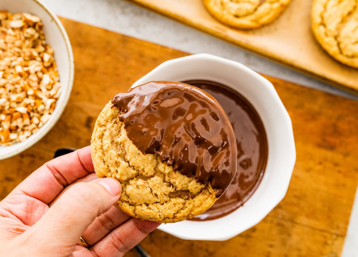 pretzel cookie being dipped in melted chocolate.