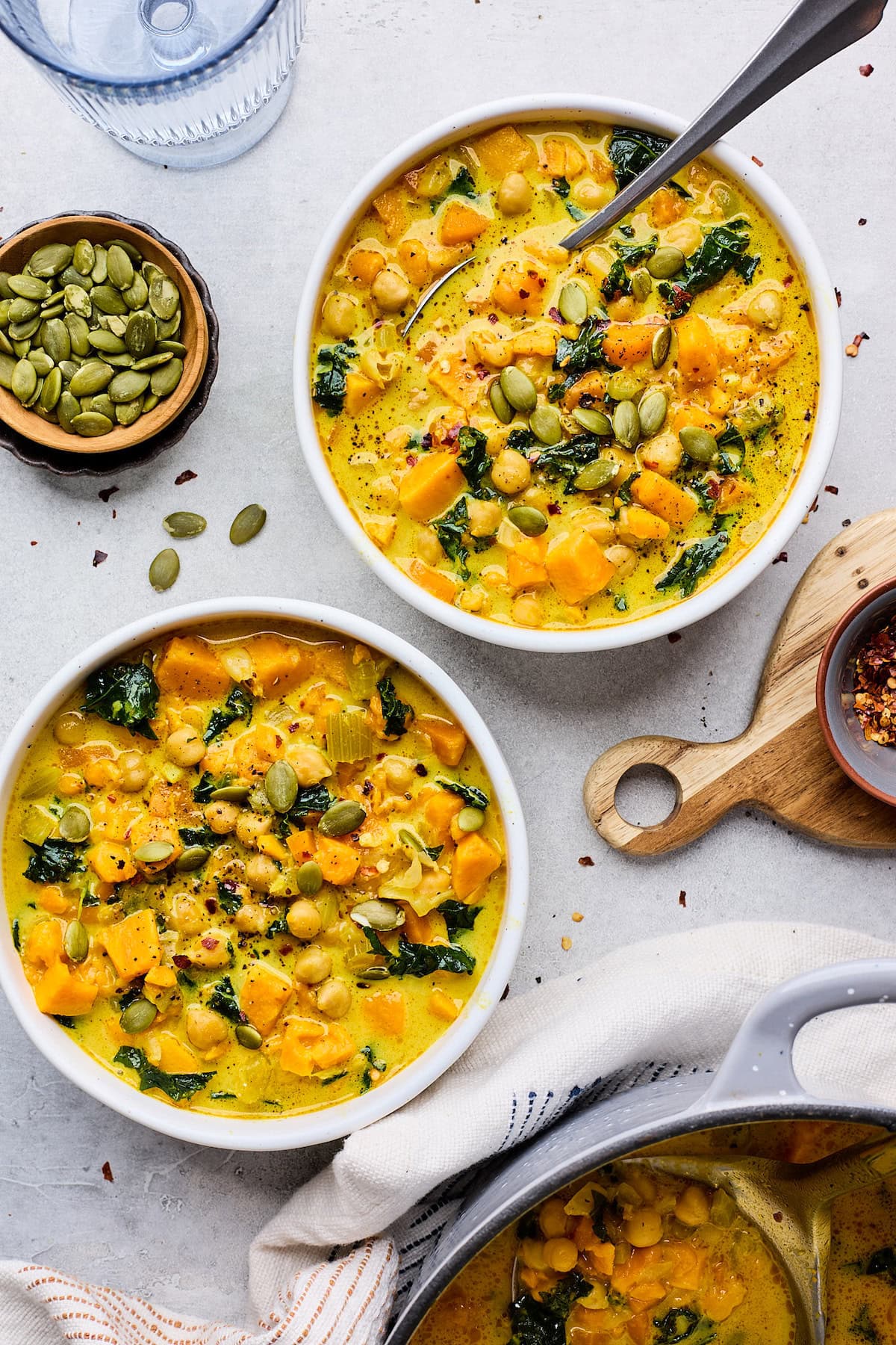 Creamy Coconut Ginger Sweet Potato Soup in bowls with pepitas as garnish.