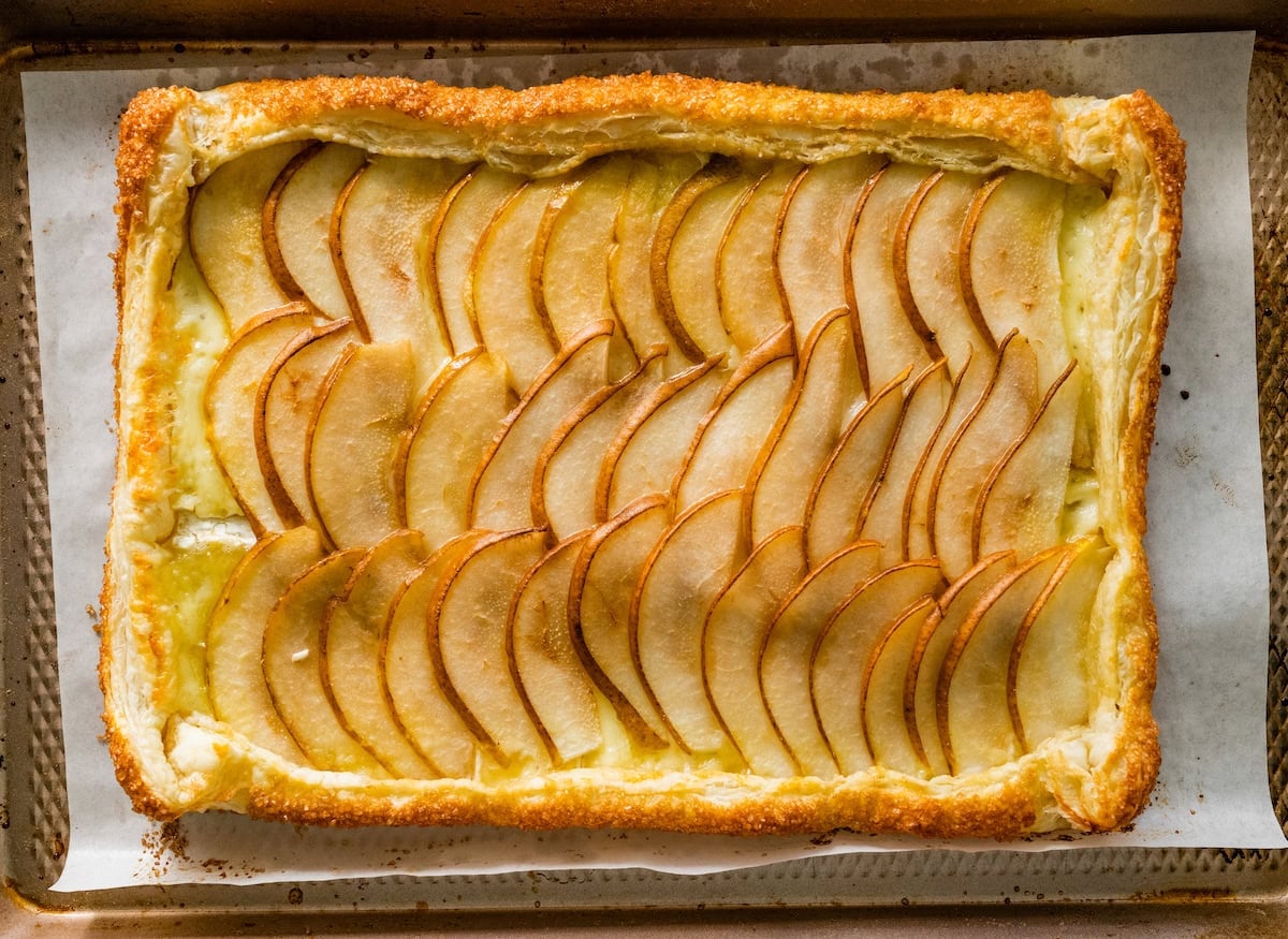 pear brie puff pastry tart on baking sheet.