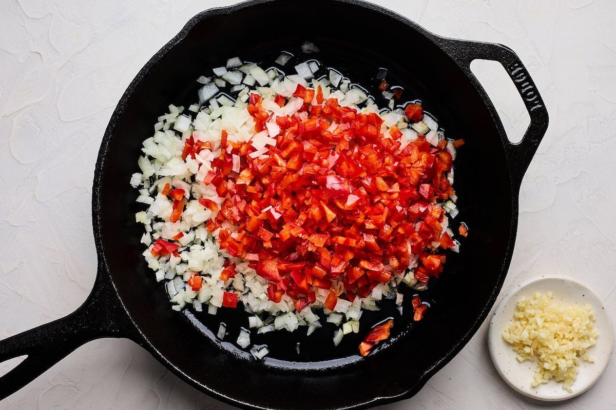onion and red peppers cooking in cast iron skillet with garlic to make black bean burger.