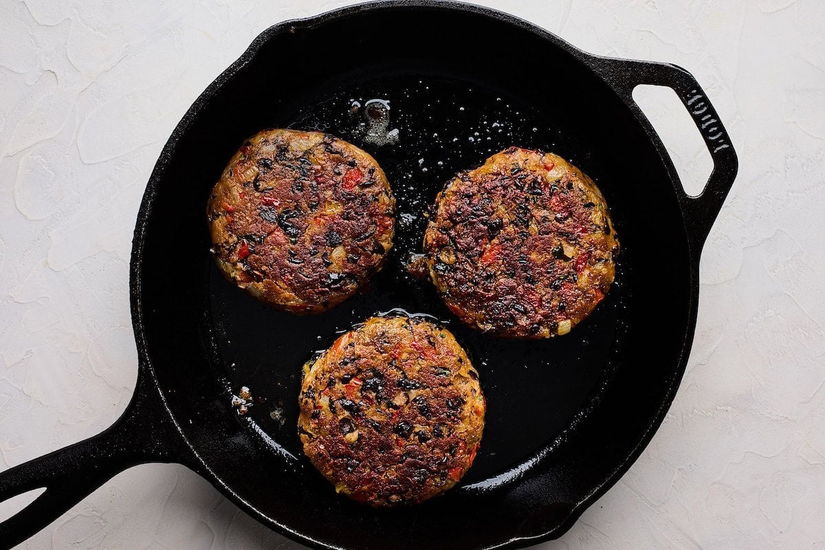 black bean burgers cooking in cast iron skillet.
