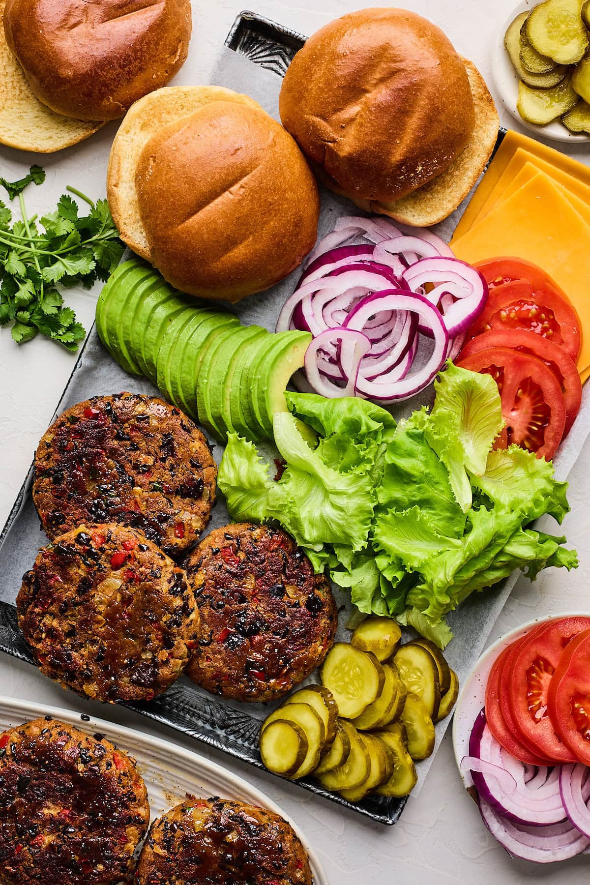 black bean burger patties with toppings and buns on tray.