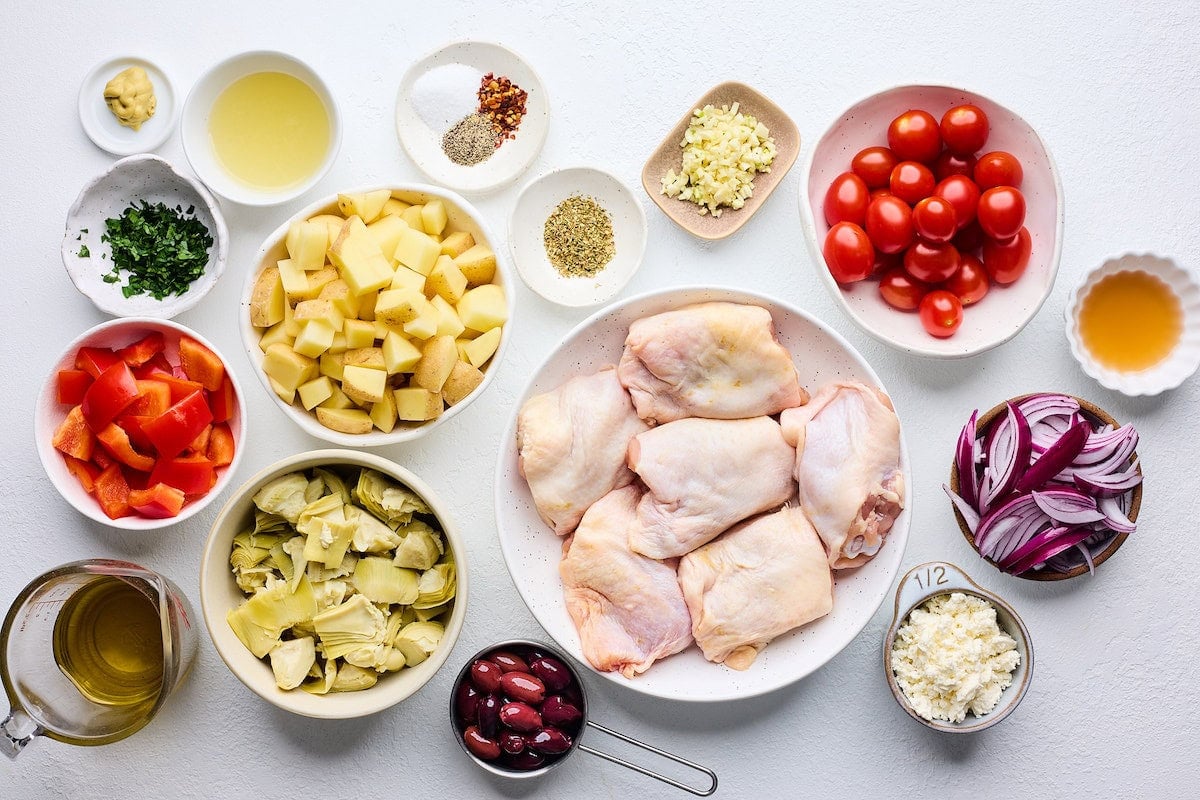 ingredients in bowls to make Greek sheet pan chicken.