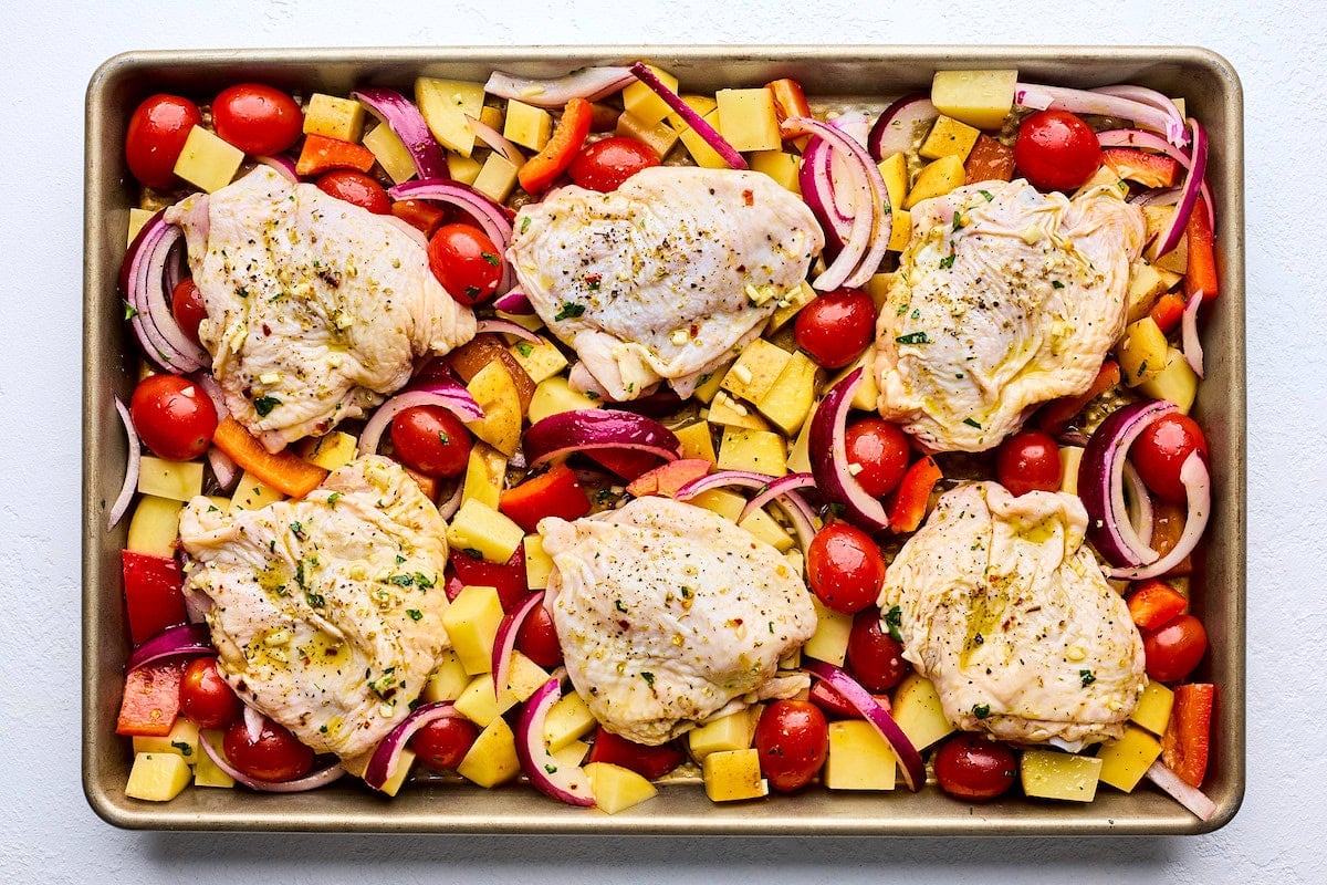 chicken thighs and vegetables on sheet pan ready to go into the oven.