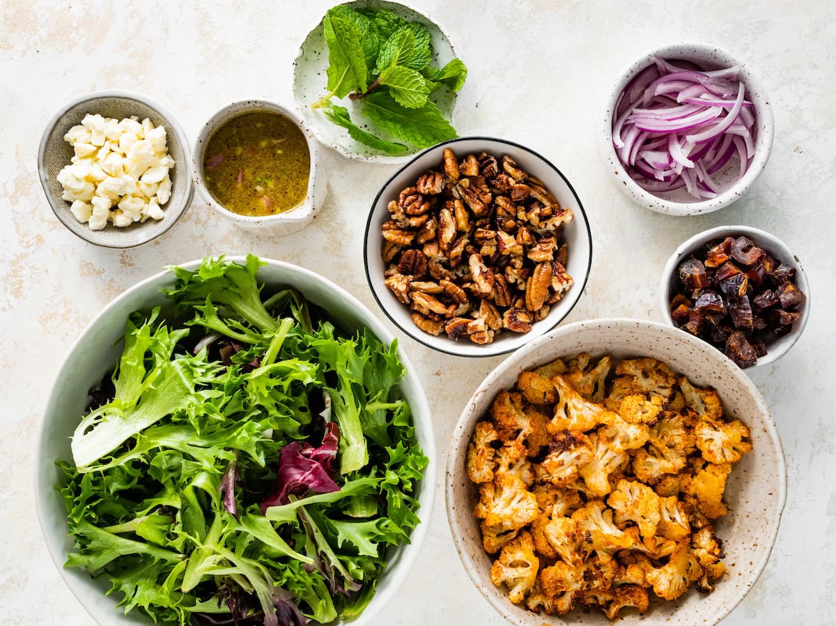ingredients in bowls to make roasted cauliflower salad with dates and pecans.