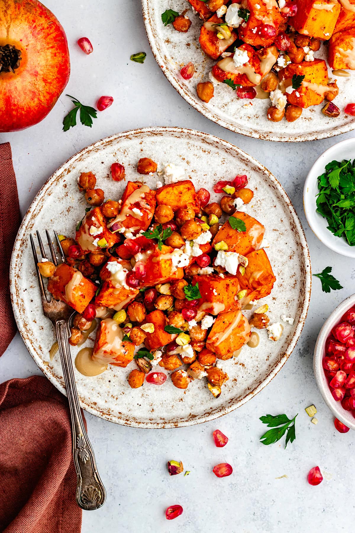 Roasted Sweet Potatoes and Chickpeas with pomegranate, feta, pistachios, and maple tahini on plate with fork.