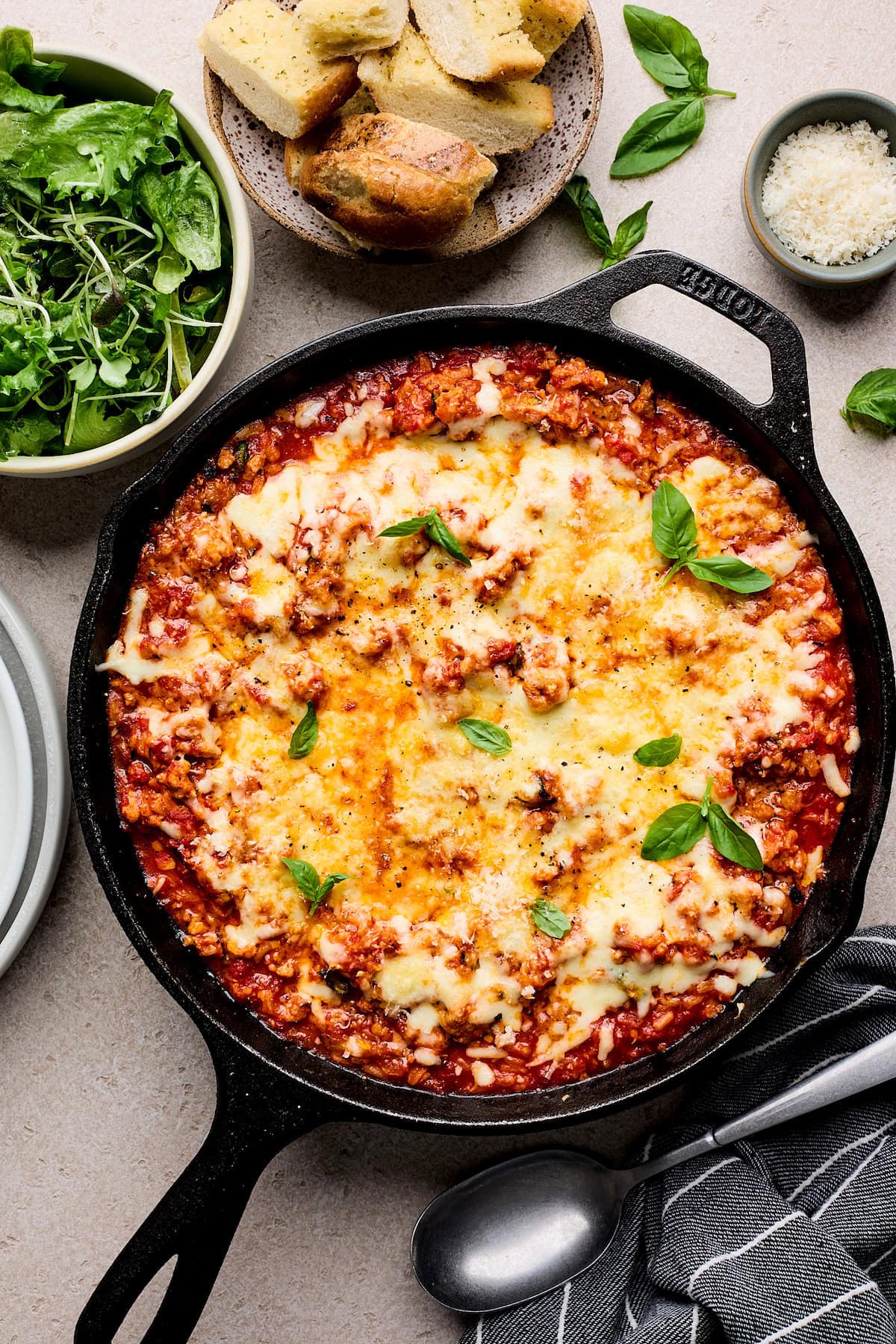 cheesy ground turkey rice skillet with marinara sauce garnished with fresh basil in cast iron skillet.