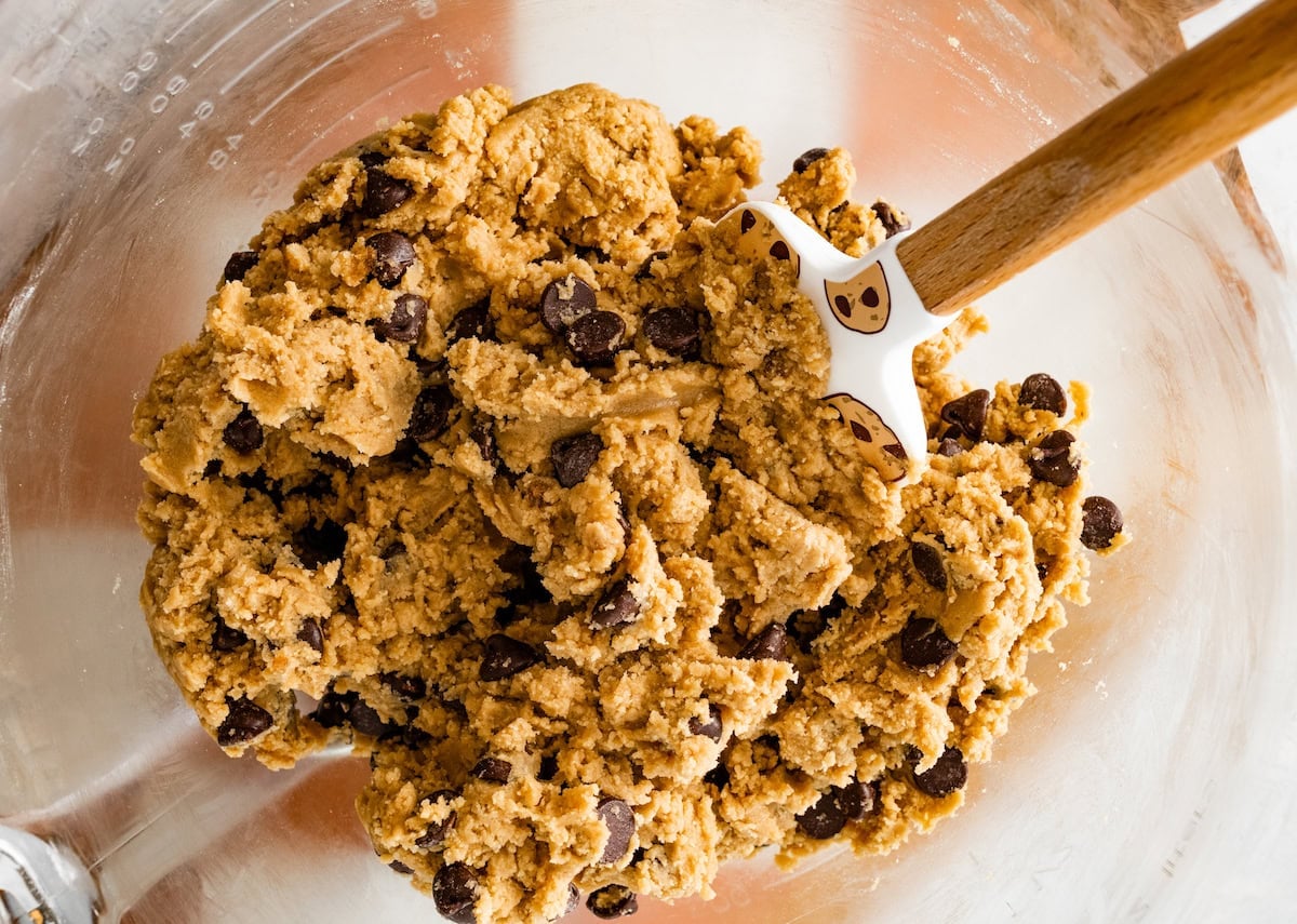 chocolate chip cookie bar dough in mixing bowl with spatula.