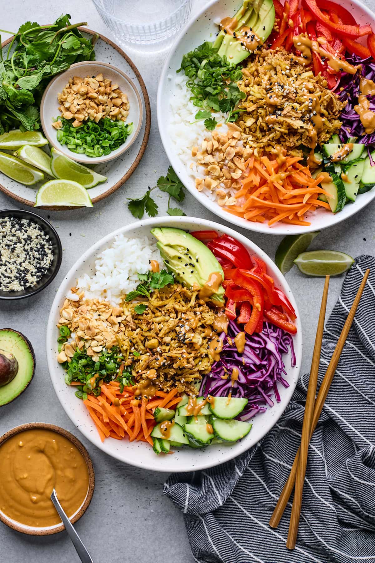 shredded tofu peanut bowls with rice and colorful veggies, herbs, lime wedges, and peanut sauce.