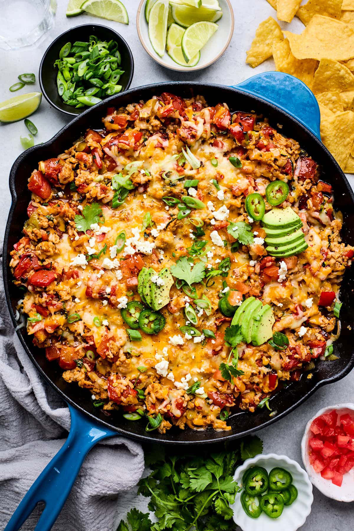 cheesy ground turkey taco skillet topped with avocado, cilantro, green onion, and jalapeño slices.