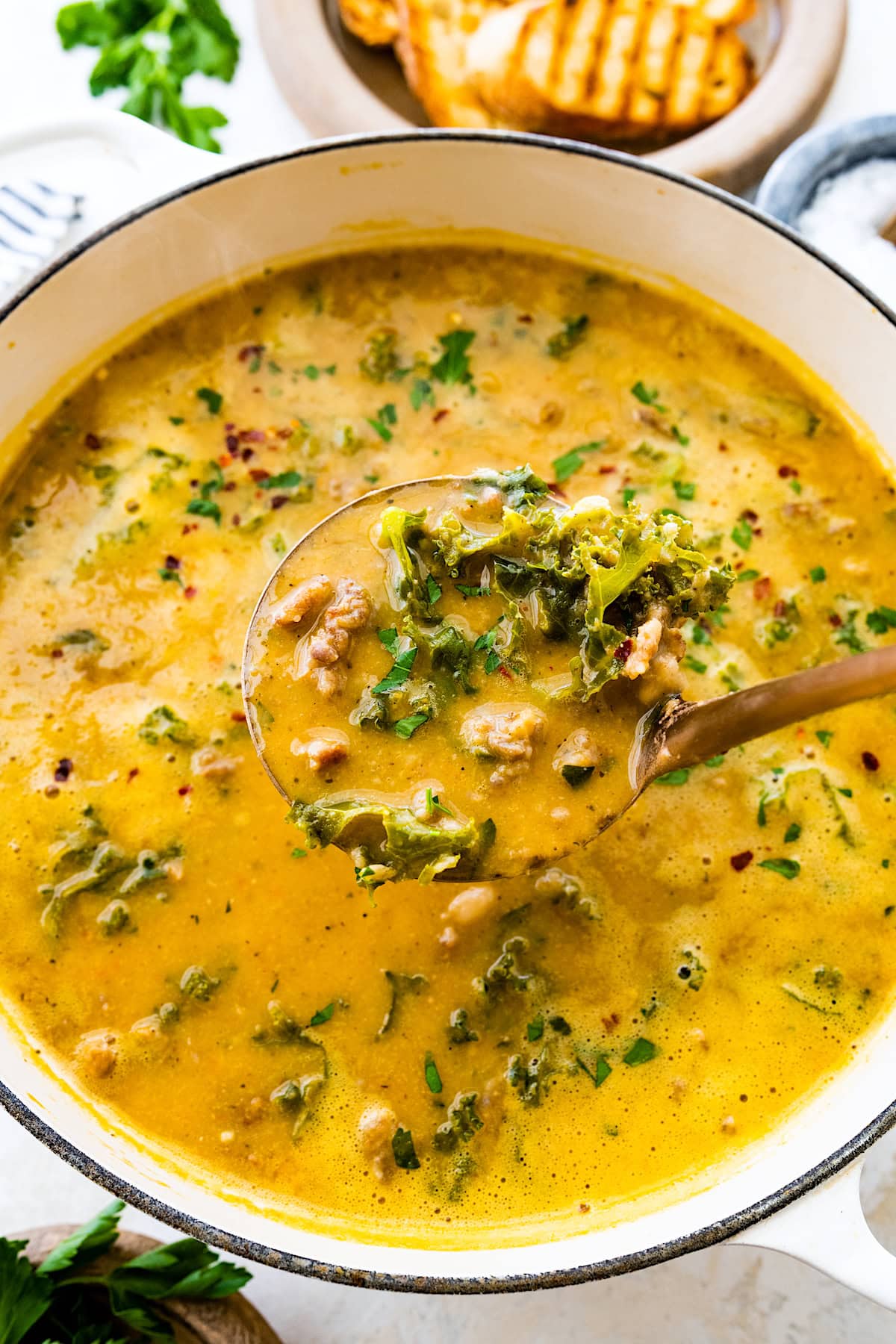 sausage kale white bean soup with in pot with fresh herbs.