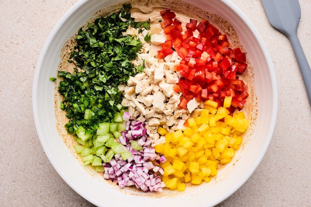 bell peppers, red onion, celery, cilantro, and chicken in a mixing bowl with creamy Greek yogurt taco dressing.