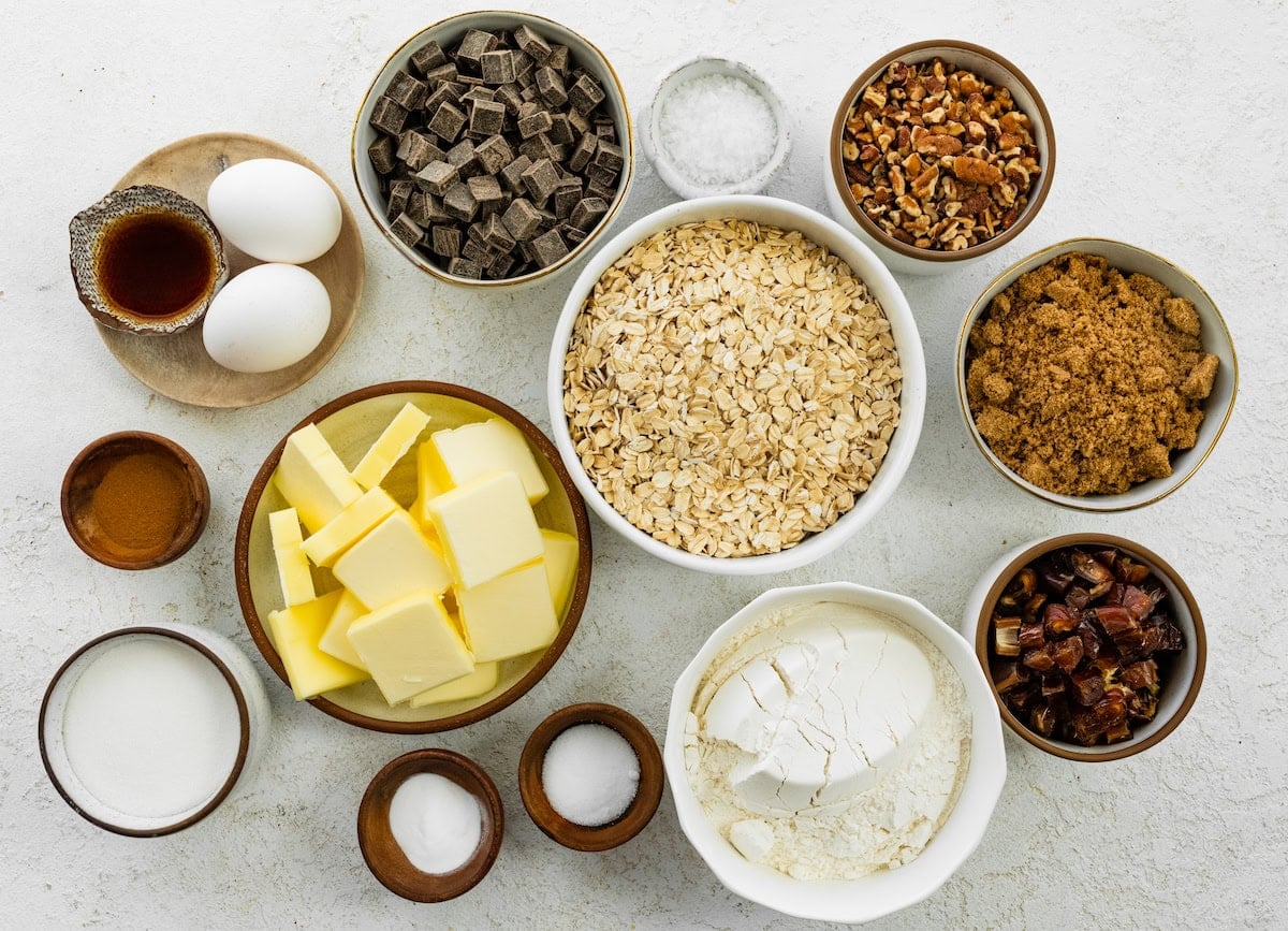 ingredients in bowls to make brown butter oatmeal cookies with pecans, dates, and chocolate chunks.