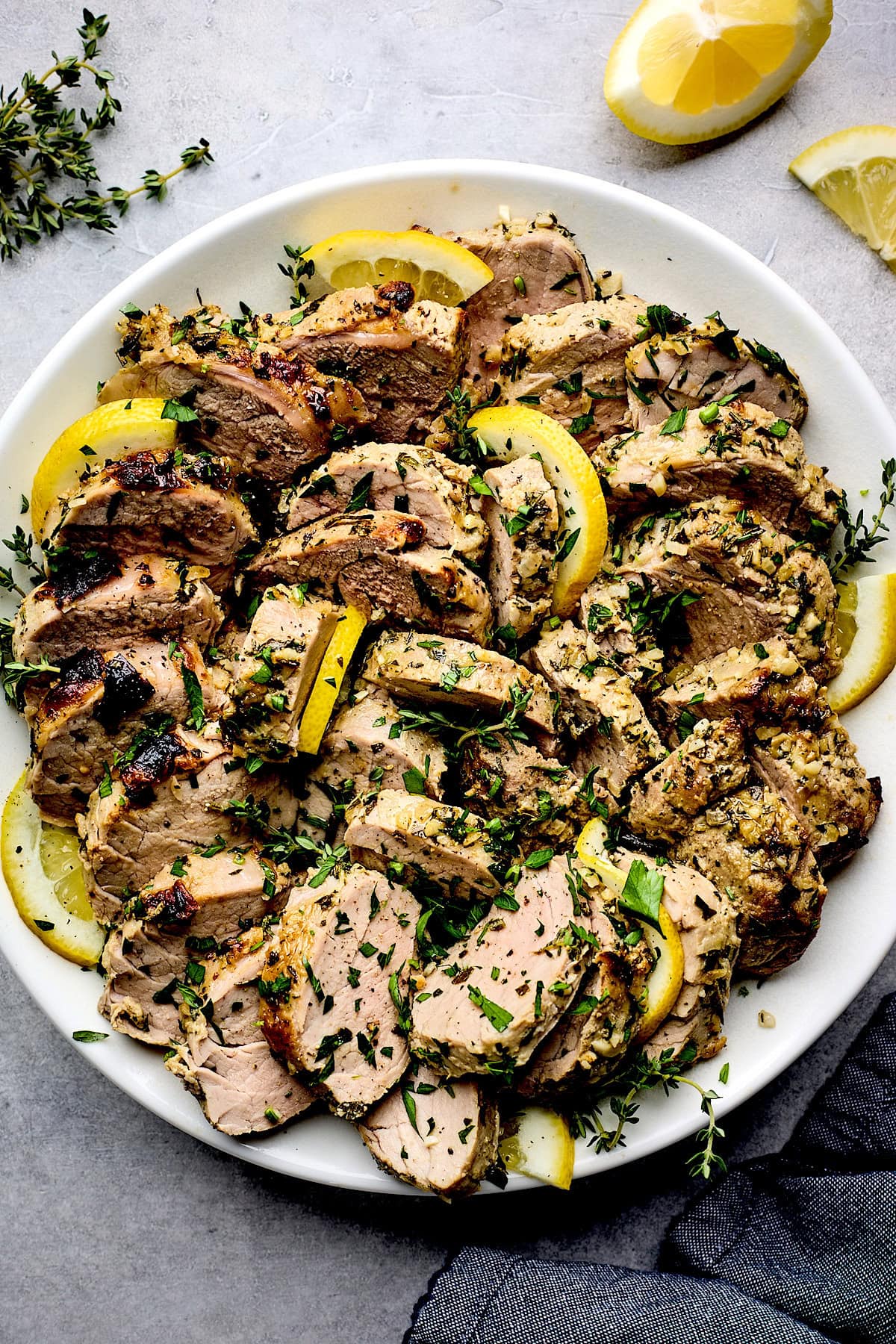 lemon herb pork tenderloin on plate with lemon slices.