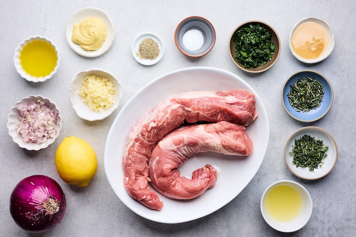 2 pork tenderloins on platter and ingredients in bowls to make lemon herb pork tenderloin.
