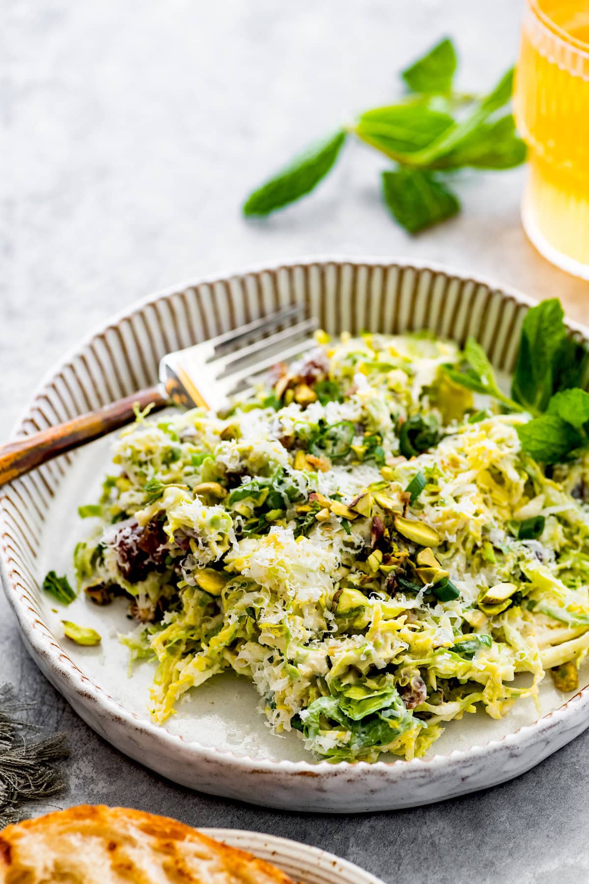 Brussels Sprouts Salad with Dates, Parmesan Cheese, Pistachios & Creamy Lemon Dressing on plate with fork.