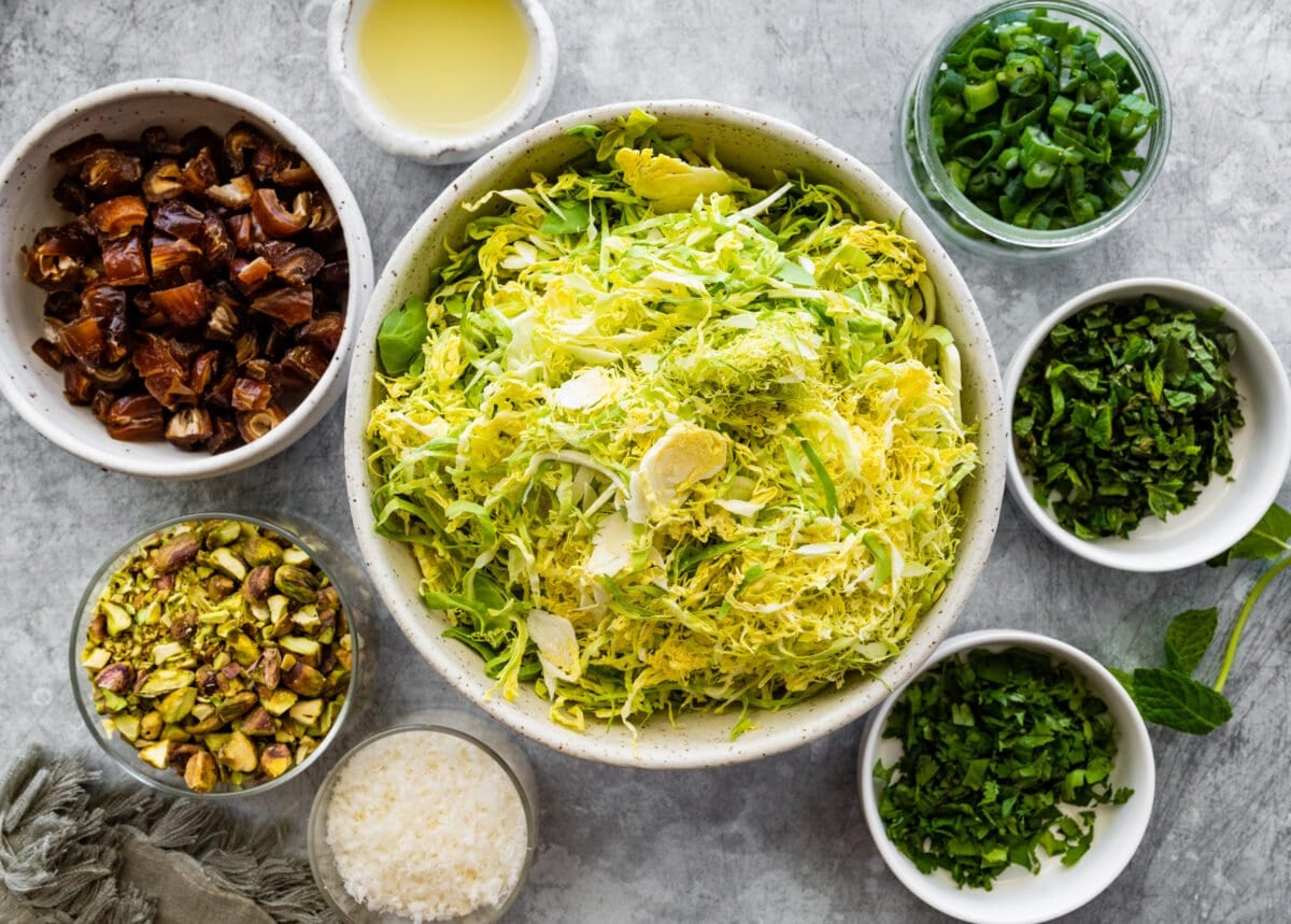 ingredients in bowls to make Brussels Sprouts Salad with Dates, Parmesan Cheese, Pistachios & Creamy Lemon Dressing.