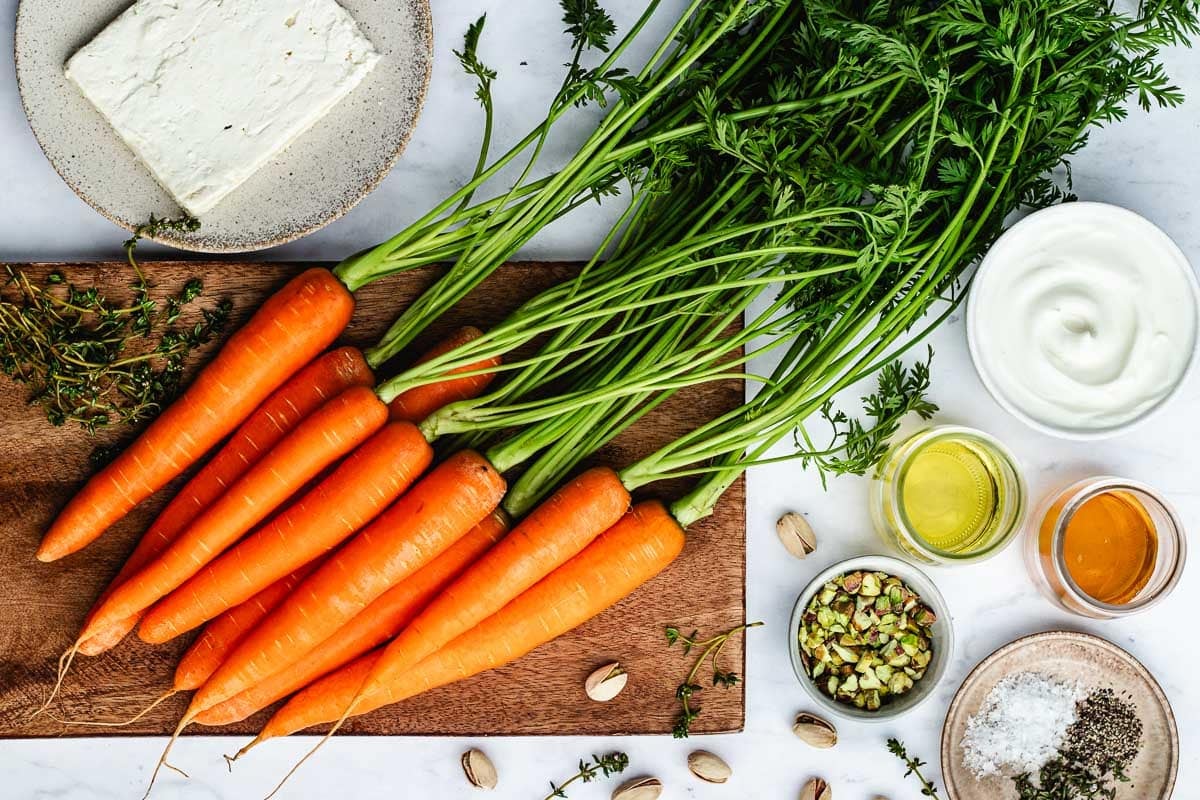carrots on cutting board and ingredients in bowls to make roasted carrots with whipped feta.