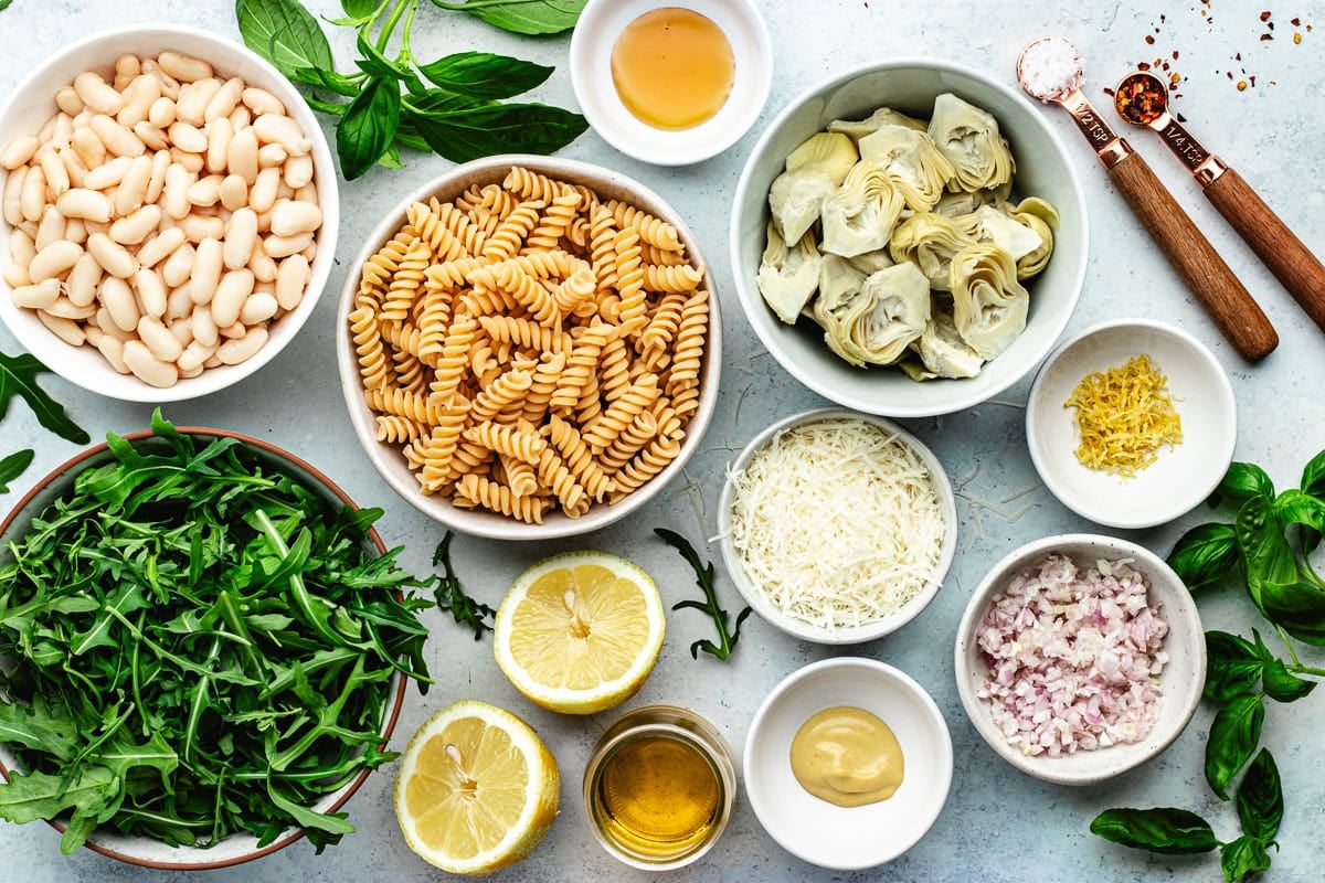 ingredients in bowls to make lemon artichoke arugula pasta salad.