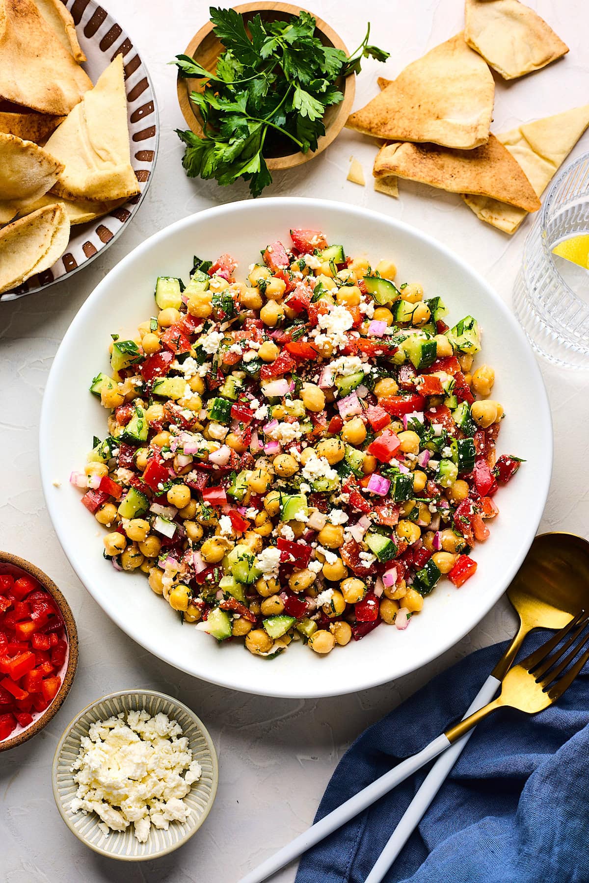 Mediterranean Chickpea Salad in bowl with cucumber, tomato, red pepper, red onion, herbs, and feta.