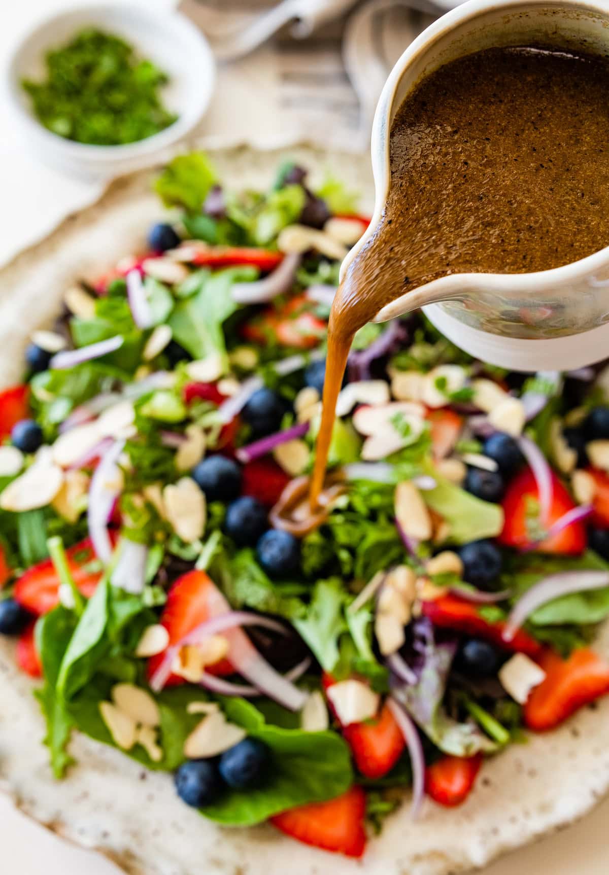 balsamic vinaigrette being poured over grilled halloumi berry salad.