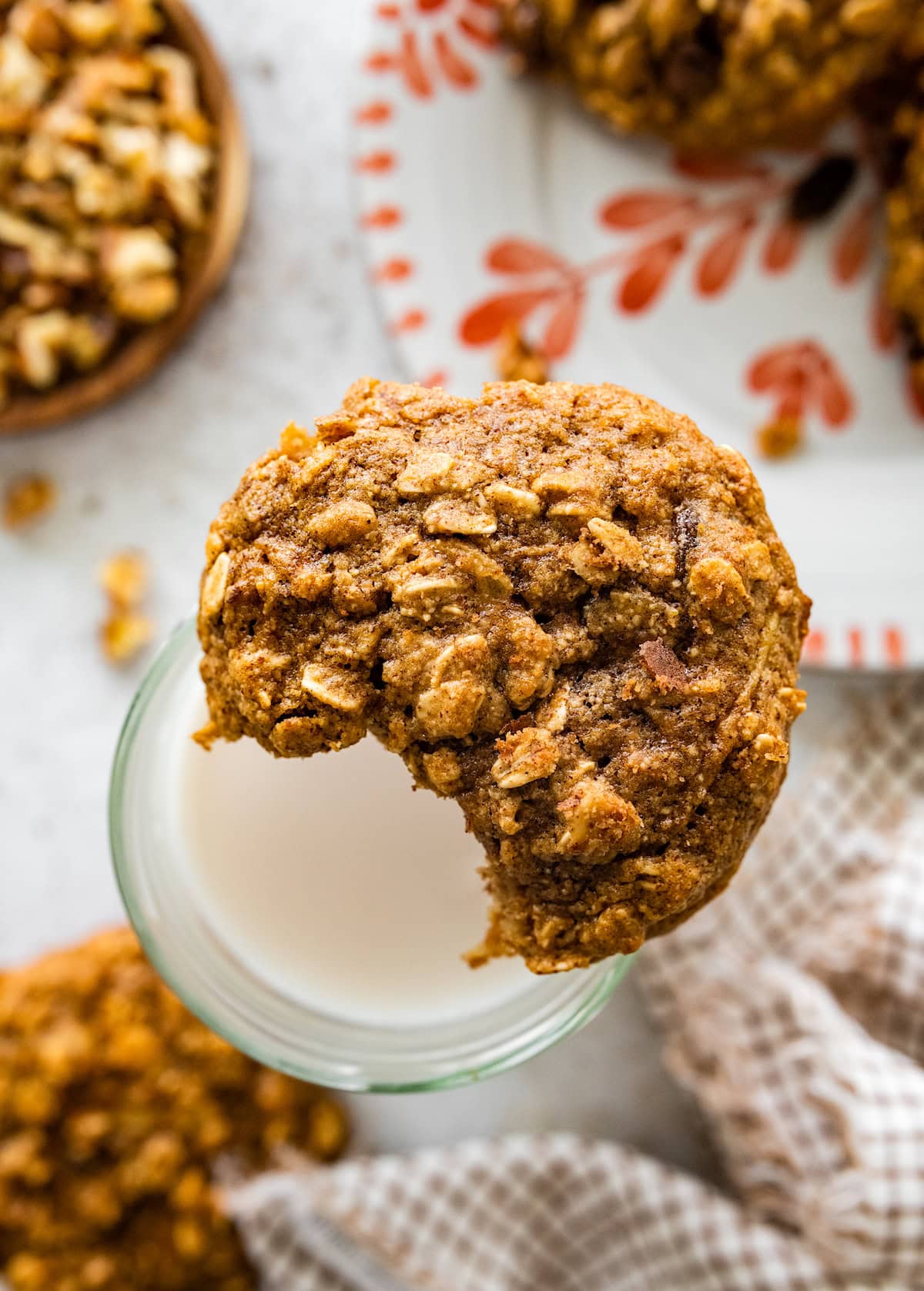 apple breakfast cookie with a bit taken out on top of glass of milk. 