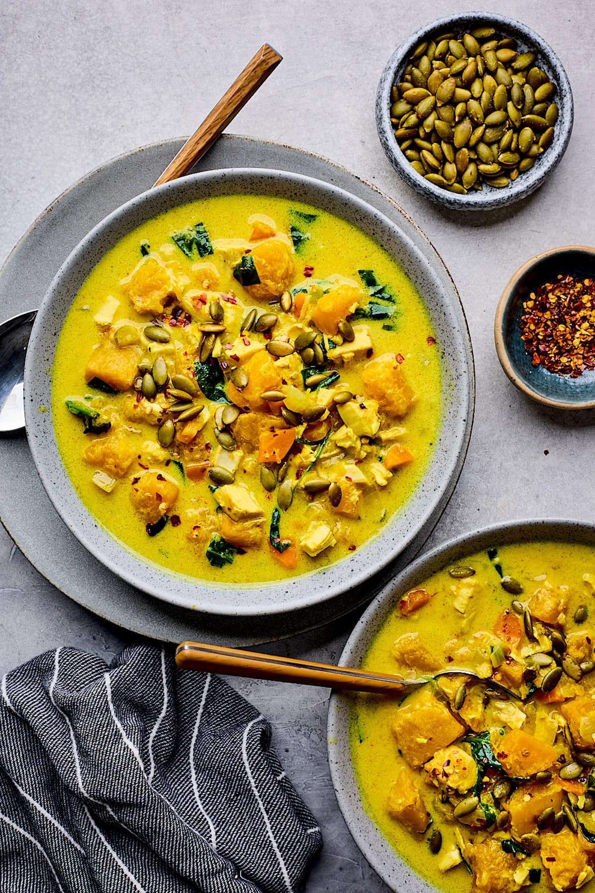Creamy Coconut Butternut Squash Chicken Soup in bowls topped with pepitas.