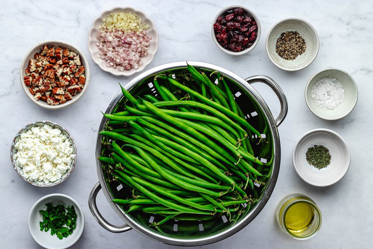 ingredients in bowls to make green beans with pecan cranberry feta crumble.