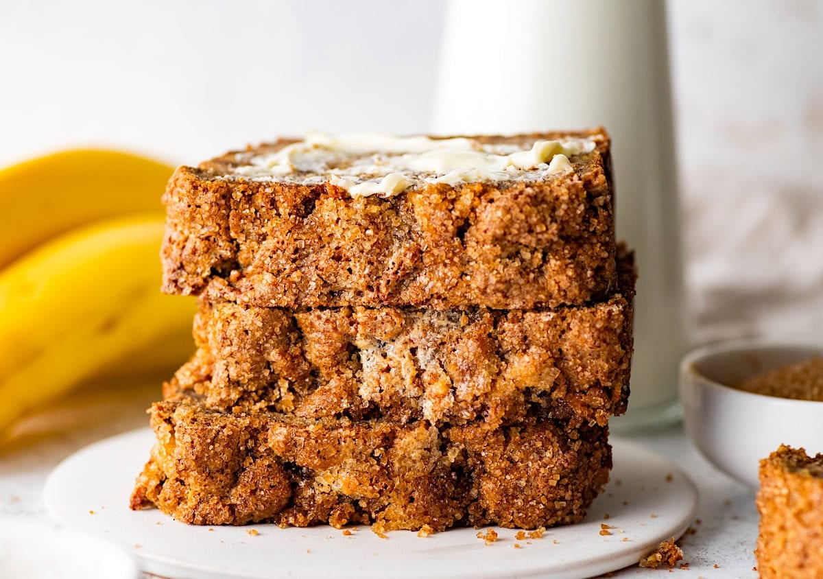 stack of 3 banana bread slices on plate with butter.